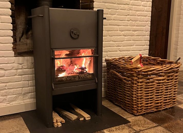 Ruime woonkamer met houten balken en open haard in vakantiehuis Udenhout, Hart van Brabant.