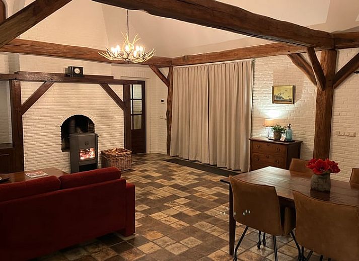 Ruime woonkamer met houten balken en open haard in vakantiehuis Udenhout, Hart van Brabant.
