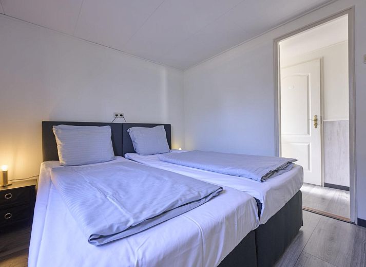 Gezellige zithoek in 't Kaatsheuveltje 7, vakantiehuis in Kaatsheuvel, Noord Brabant, met bloemen en comfortabele bank.