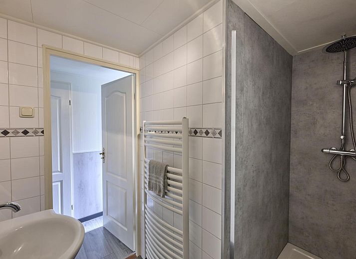 Gezellige zithoek in 't Kaatsheuveltje 7, vakantiehuis in Kaatsheuvel, Noord Brabant, met bloemen en comfortabele bank.