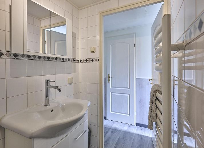 Gezellige zithoek in 't Kaatsheuveltje 7, vakantiehuis in Kaatsheuvel, Noord Brabant, met bloemen en comfortabele bank.