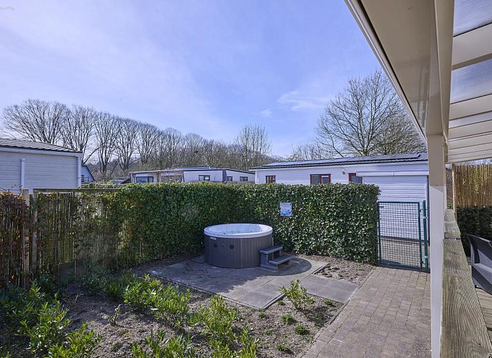 Gezellige zithoek in 't Kaatsheuveltje 7, vakantiehuis in Kaatsheuvel, Noord Brabant, met bloemen en comfortabele bank.