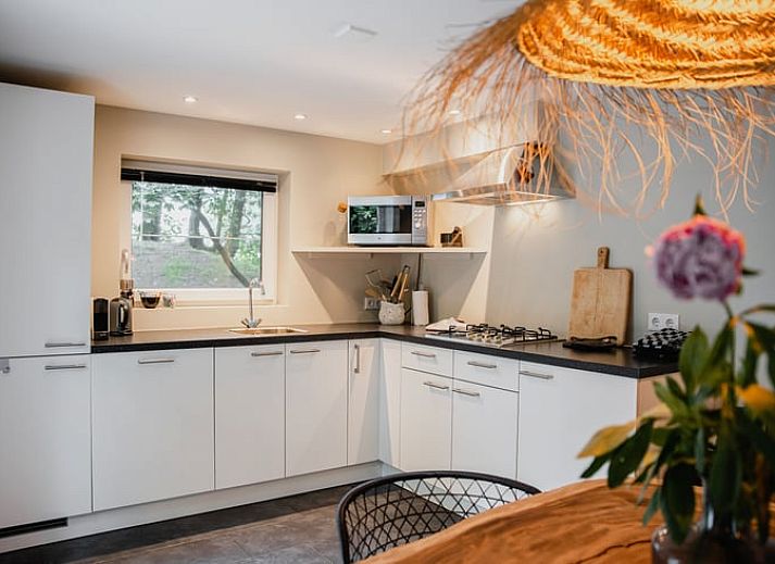 Gemuetliches Wohnzimmer im Ferienhaus in Leende, Herz von Brabant, Nordbrabant mit bequemem Sofa und Gartenblick.