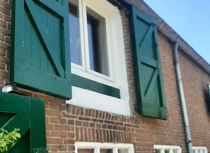 Vakantiehuisje in Hank, een charmant verblijf in Hart van Brabant, Noord Brabant, omgeven door groene bomen en een traditionele bakstenen gevel.