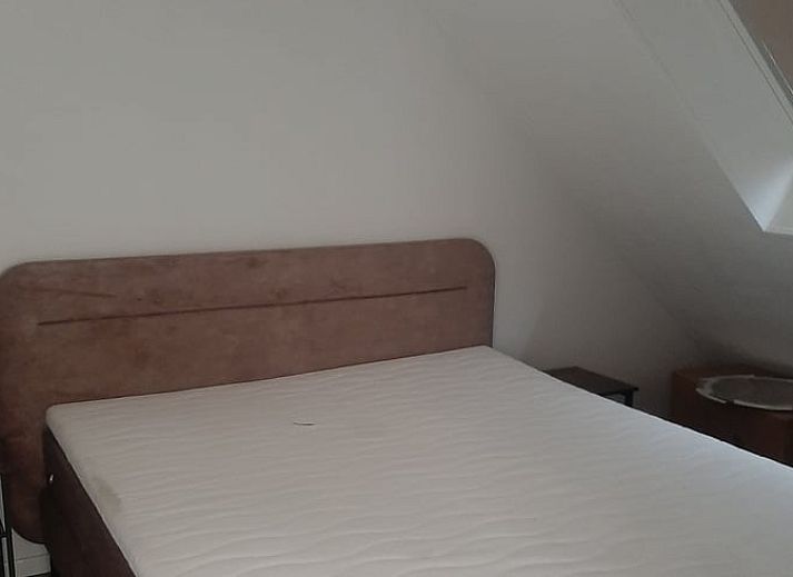 Vakantiehuisje in Hank, een charmant verblijf in Hart van Brabant, Noord Brabant, omgeven door groene bomen en een traditionele bakstenen gevel.