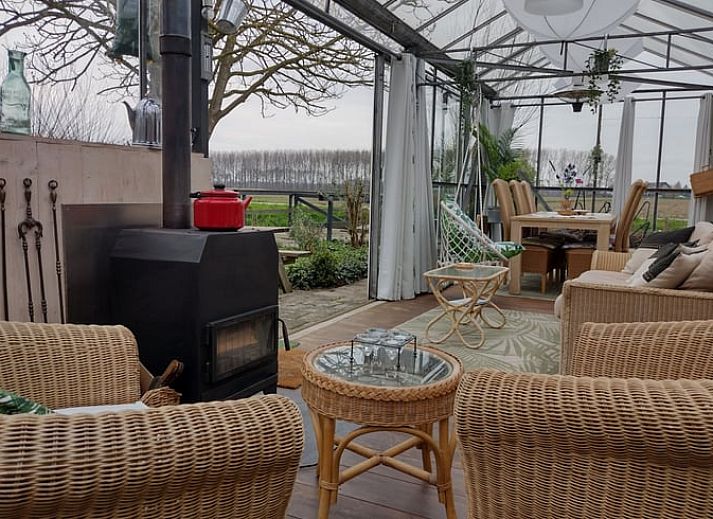 Lichte en ruime binnenruimte van Vakantiehuisje in Hank, Noord Brabant, met glazen wanden en comfortabele zithoek, ideaal voor ontspanning.
