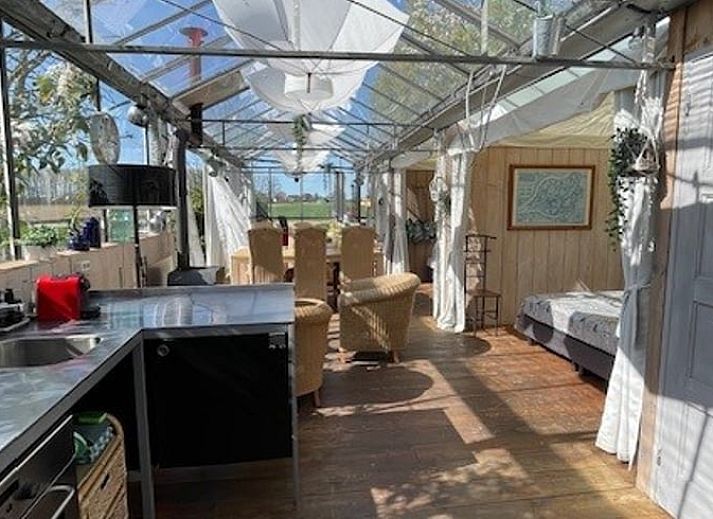 Gezellige binnenruimte in Vakantiehuisje in Hank, Hart van Brabant, met retro meubels en uitzicht op groene natuur.