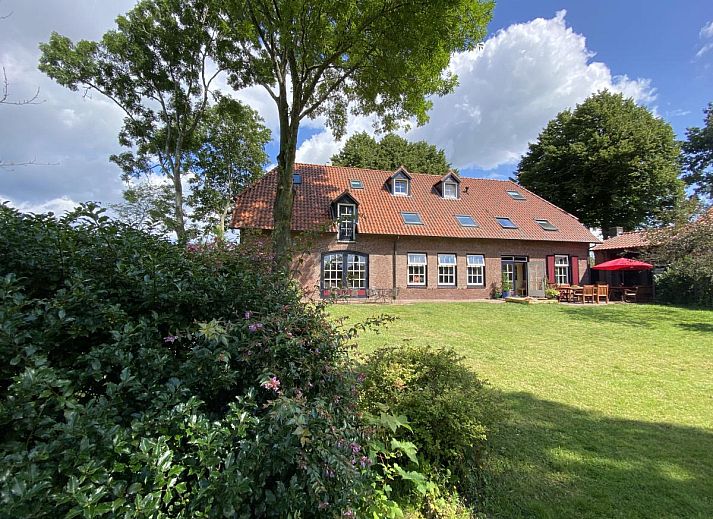 Terras van De Meerenhoeve in Mill, Noord Brabant, met houten meubels en uitzicht op de tuin.