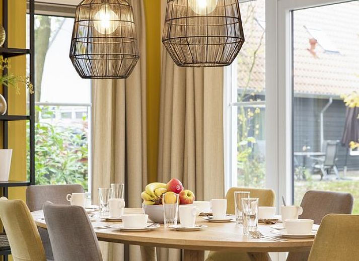 Moderne woonkamer in De Vers 6-persoons bungalow 6C2, Overloon, met open keuken en houten vloer.