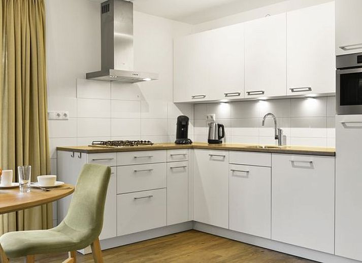 Moderne woonkamer in De Vers 6-persoons bungalow 6C2, Overloon, met open keuken en houten vloer.