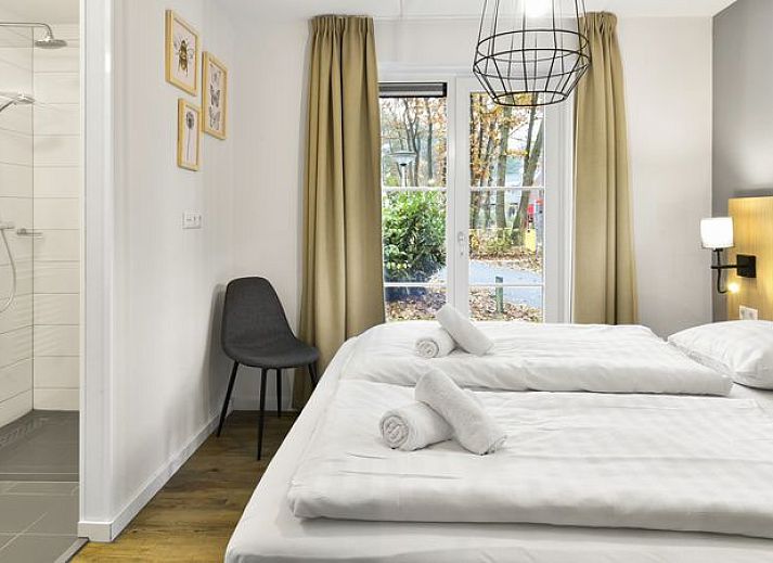Moderne woonkamer in De Vers 6-persoons bungalow 6C2, Overloon, met open keuken en houten vloer.