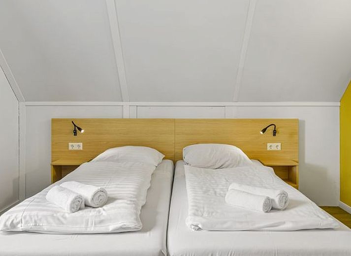 Comfortabele zithoek in De Vers 6-persoons bungalow 6C2, Overloon, met gele accenten en ruime bank.