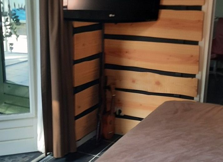 Achtertuin van vakantiehuis Grove Den in Sint-Oedenrode, Noord Brabant, met uitzicht op het grasveld en bomen.