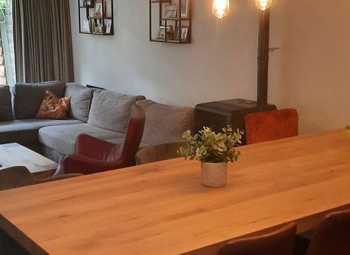 Terras met houten tafel en stoelen bij Grove Den in Sint-Oedenrode, Noord Brabant, omgeven door weelderige natuur.