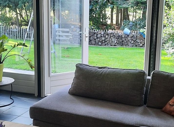 Terras met houten tafel en stoelen bij Grove Den in Sint-Oedenrode, Noord Brabant, omgeven door weelderige natuur.