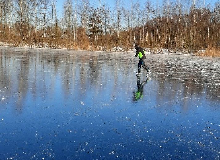 Terras met houten tafel en stoelen bij Grove Den in Sint-Oedenrode, Noord Brabant, omgeven door weelderige natuur.