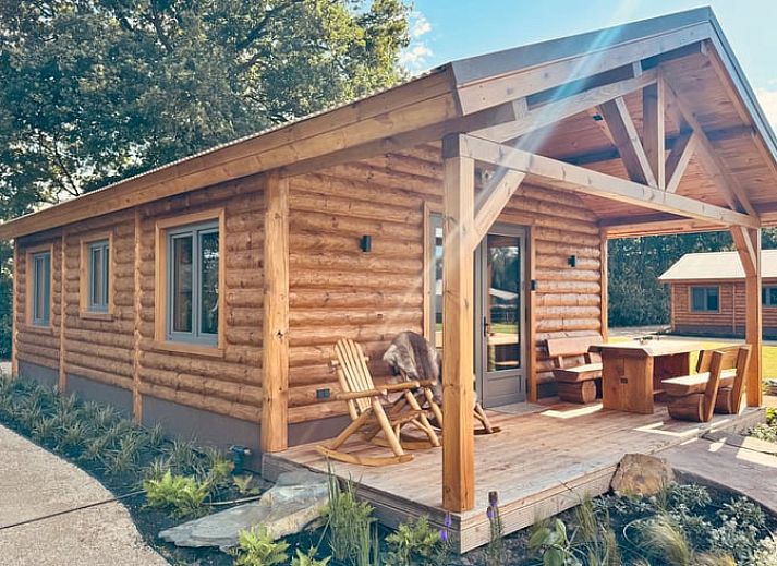 Cozy wooden cottage in Ledeacker Northeast Brabant with porch and seating area, surrounded by nature.