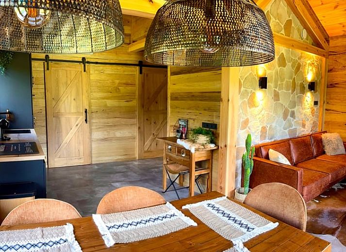 Cozy wooden cottage in Ledeacker Northeast Brabant with porch and seating area, surrounded by nature.