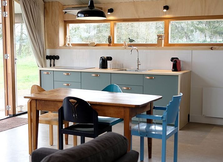 Gemuetliches Interieur eines Ferienhauses in Gilze mit Blumen und Wein, Westbrabant.