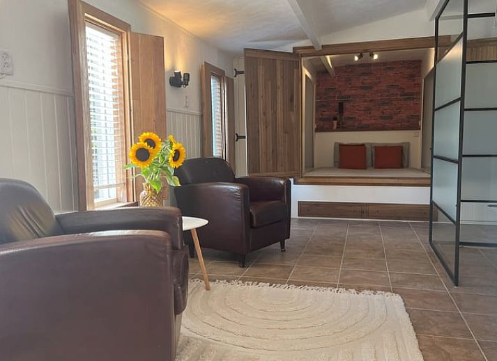 Gemuetliches Wohnzimmer im Cottage in Hoogerheide, Ferienhaus in Westbrabant, Nordbrabant mit bequemen Stuehlen und Sonnenblumen.
