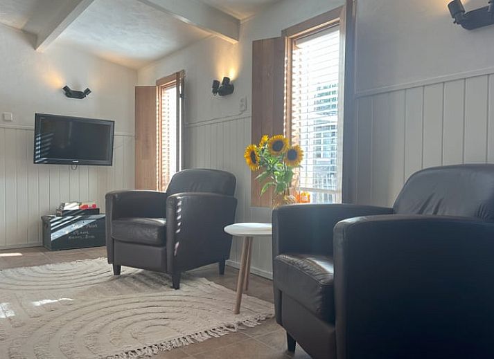 Gemuetliches Wohnzimmer im Cottage in Hoogerheide, Ferienhaus in Westbrabant, Nordbrabant mit bequemen Stuehlen und Sonnenblumen.