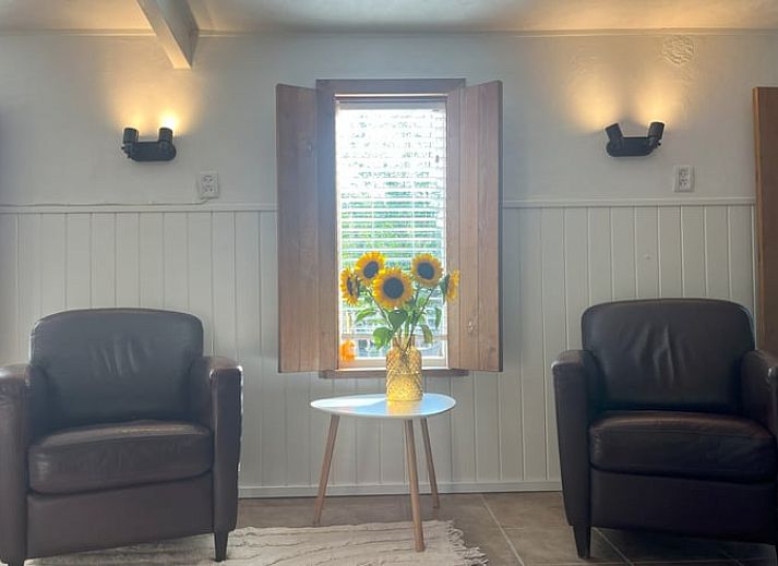 Gemuetliches Wohnzimmer im Cottage in Hoogerheide, Ferienhaus in Westbrabant, Nordbrabant mit bequemen Stuehlen und Sonnenblumen.
