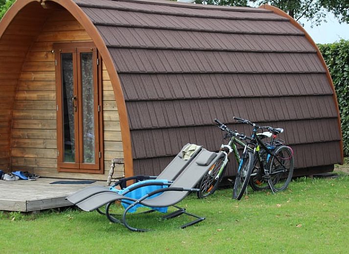 Gemuetliches Holzhaus im Cottage in Terheijden, Nordbrabant, mit Fahrraedern und Liegestuehlen auf dem Rasen.
