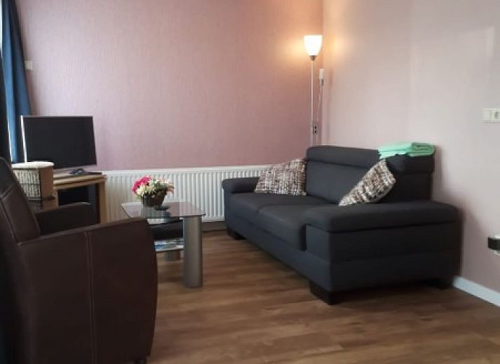 Ontspannen terras bij Huisje Welkom in Schoorl, vakantiehuis aan de Noordzeekust, Noord-Holland, met ligstoelen omgeven door groene natuur.