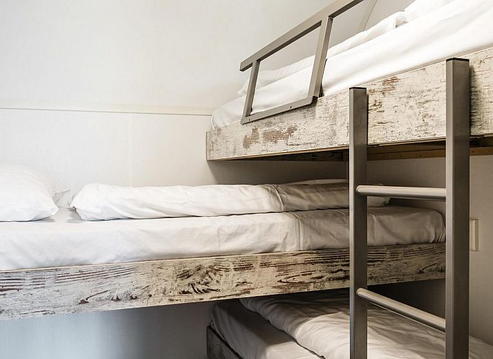 Gezellige woonkamer in Strandhuisje voor 5 personen, Julianadorp, Noordzeekust, met uitzicht op groene tuin en comfortabele zithoek.