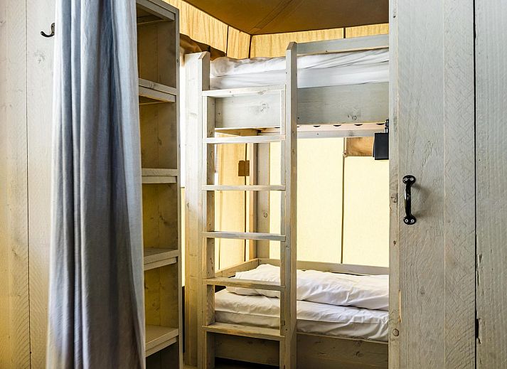 Innenansicht des Strandzeltes fuer 6 Personen in Julianadorp, Nordholland. Gemuetliche Glamping-Lodge mit Holzinterieur und komfortabler Sitzecke.