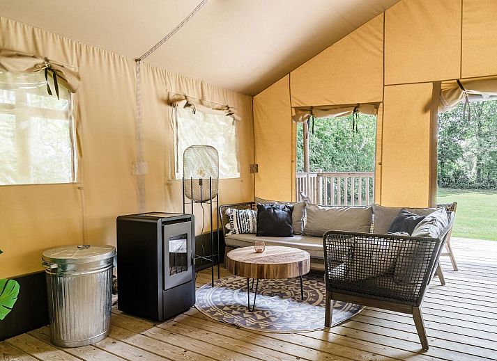 Innenansicht des Strandzeltes fuer 6 Personen in Julianadorp, Nordholland. Gemuetliche Glamping-Lodge mit Holzinterieur und komfortabler Sitzecke.