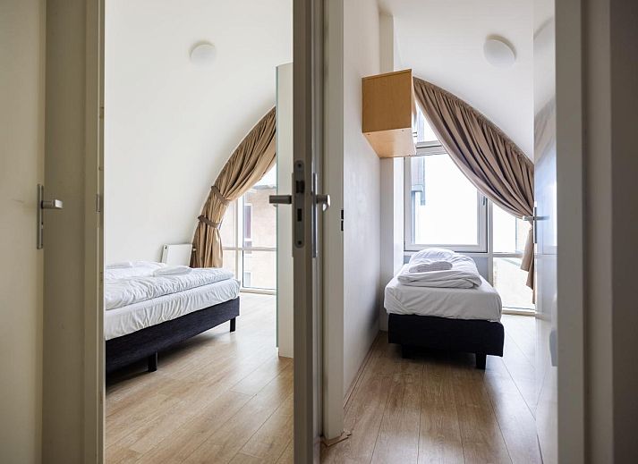 Gemuetliches Wohnzimmer des Ferienhauses Zeebaars in Egmond aan Zee, Nordholland, mit Blick auf die Terrasse an der Nordseekueste.