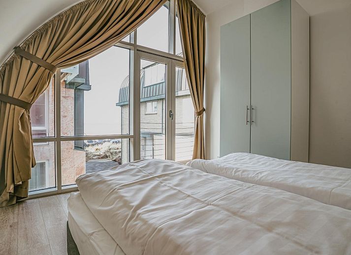 Gemuetliches Wohnzimmer des Ferienhauses Zeebaars in Egmond aan Zee, Nordholland, mit Blick auf die Terrasse an der Nordseekueste.