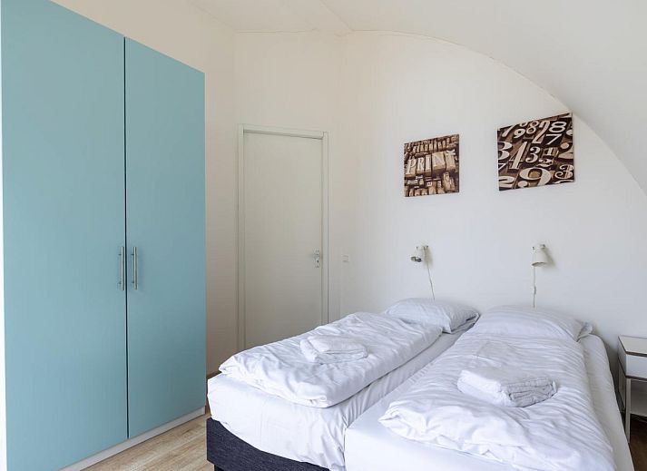 Gemuetliches Wohnzimmer des Ferienhauses Zeebaars in Egmond aan Zee, Nordholland, mit Blick auf die Terrasse an der Nordseekueste.