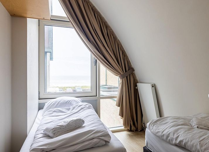 Gemuetliches Wohnzimmer des Ferienhauses Zeebaars in Egmond aan Zee, Nordholland, mit Blick auf die Terrasse an der Nordseekueste.