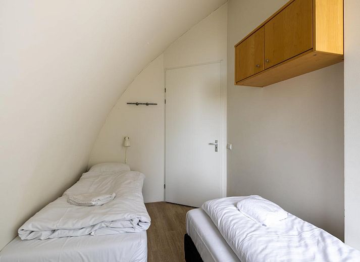 Gemuetliches Wohnzimmer des Ferienhauses Zeebaars in Egmond aan Zee, Nordholland, mit Blick auf die Terrasse an der Nordseekueste.