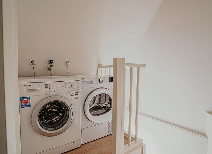Gemuetliches Wohnzimmer des Ferienhauses Zeebaars in Egmond aan Zee an der Nordseekueste mit komfortabler Sitzecke und Blick auf die Terrasse.