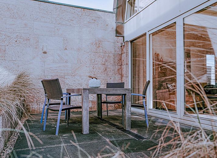 Gemuetliches Wohnzimmer des Ferienhauses Zeebaars in Egmond aan Zee an der Nordseekueste mit komfortabler Sitzecke und Blick auf die Terrasse.