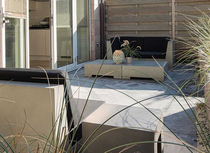 Modernes Wohnzimmer des Ferienhauses Zeebaars in Egmond aan Zee mit offener Kueche und Gartenblick, Nordseekueste, Nordholland.