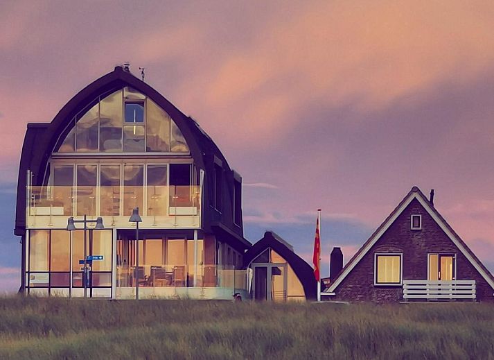 Modernes Wohnzimmer des Ferienhauses Zeebaars in Egmond aan Zee mit offener Kueche und Gartenblick, Nordseekueste, Nordholland.