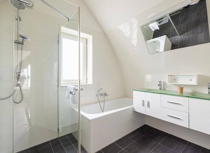 Cozy living room of vacation home De Platvis in Egmond aan Zee, North Sea coast, North Holland, with comfortable furnishings and a view of the terrace.