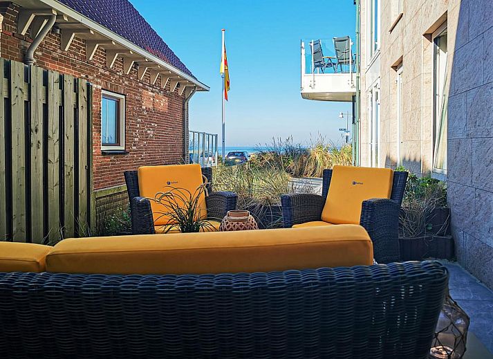 Bright living room in holiday home De Platvis, Egmond aan Zee, with large windows and modern furnishings on the North Sea coast in North Holland.