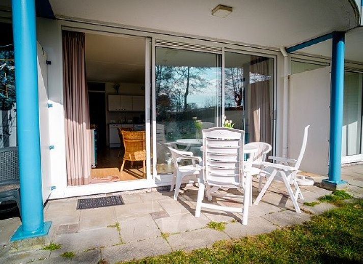 Gezellige woonkamer van Bad8 appartement in Callantsoog met rieten stoelen en blauwe accenten.
