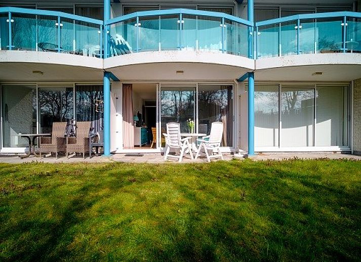 Gezellige woonkamer van Bad8 appartement in Callantsoog met rieten stoelen en blauwe accenten.