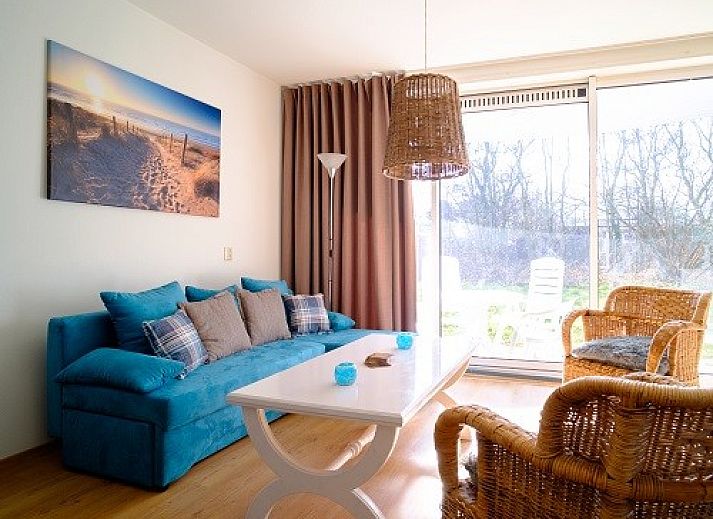 Gezellige woonkamer van Bad8 appartement in Callantsoog met rieten stoelen en blauwe accenten.