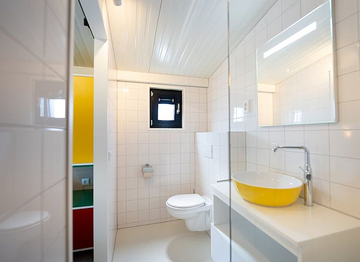 Gezellige woonkamer van Tulip Mania 4 vakantiehuis in Callantsoog, Noord-Holland, met kleurrijk interieur en moderne keuken aan de Noordzeekust.