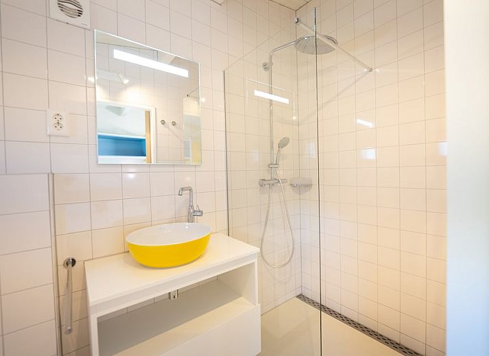 Gezellige woonkamer van Tulip Mania 4 vakantiehuis in Callantsoog, Noord-Holland, met kleurrijk interieur en moderne keuken aan de Noordzeekust.