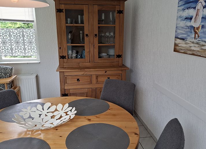 Frontansicht des Ferienhauses NH549 in Callantsoog, Nordseekueste, Nordholland, mit roten Tueren und gruener Umgebung.