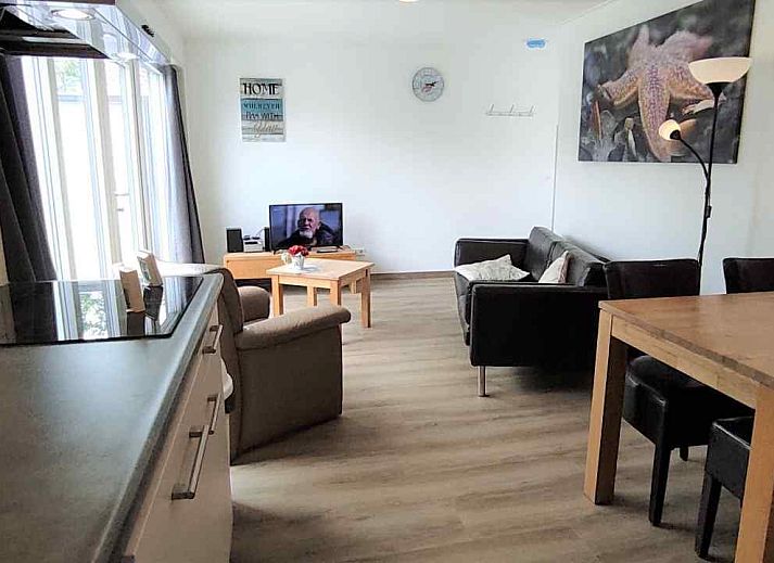 Terrasse des Ferienhauses NH213 in Callantsoog, Nordseekueste, mit Gartenmoebeln aus Holz und gruener Umgebung.