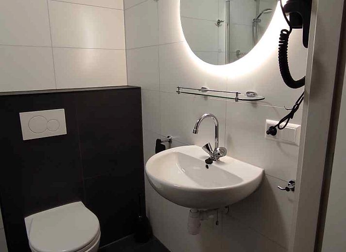 Gemuetliches Wohnzimmer des NH213 Ferienhauses in Callantsoog, Nordholland, mit bequemen Sofas und Essecke.